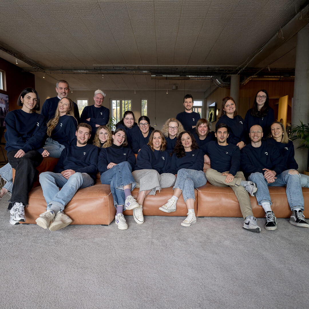 Photo de groupe de l’équipe Références, réunie dans un espace de travail convivial, vêtue de sweats bleu marine.