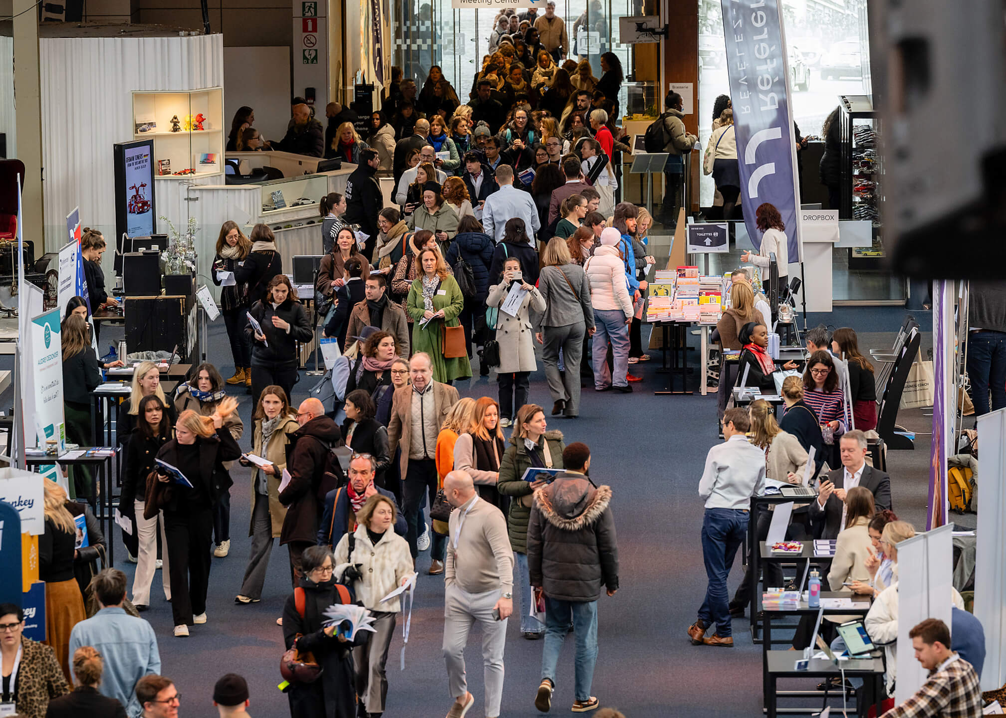 Grande affluence de visiteurs circulant entre les stands d’un salon professionnel intérieur.